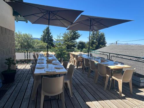 a row of tables and chairs on a deck with umbrellas at Aupalya Gîte Le Logis Catalan in Font-Romeu