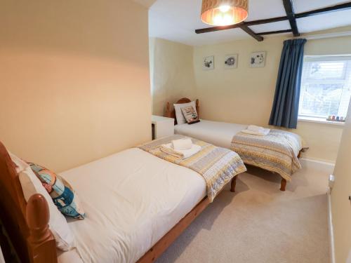 a bedroom with two beds and a window at Cobbler's Cottage in Norwich
