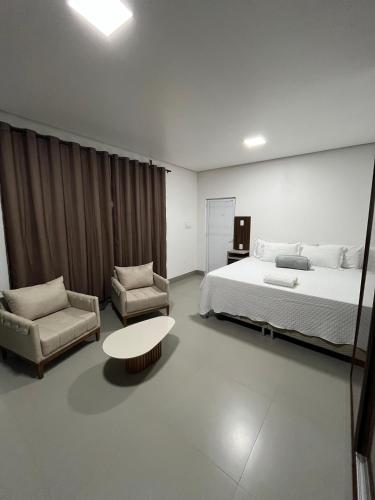 a bedroom with a bed and a table and a chair at Villa Hotel in Bom Jesus da Lapa