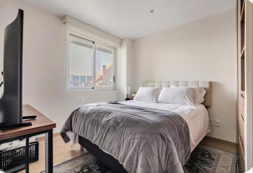 a white bedroom with a bed and a window at Polanco condo, alberca y Gym in Mexico City