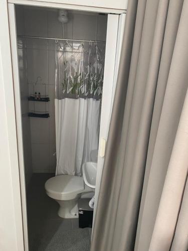 a bathroom with a toilet and a shower curtain at KIT 300- com Ar cond - 5 min do aeroporto, rodoviária e embaixadas in Brasília