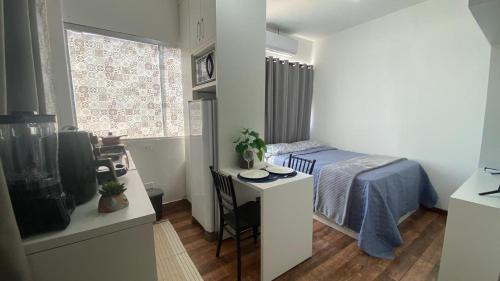 a small bedroom with a bed and a small table at KIT 300- com Ar cond - 5 min do aeroporto, rodoviária e embaixadas in Brasília