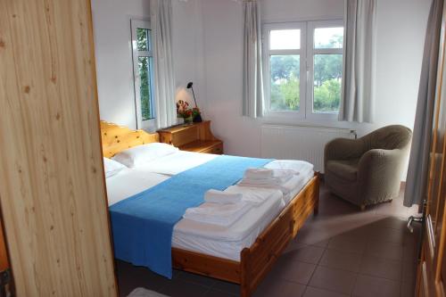 a bedroom with a bed and a chair and windows at Art.Villa.Nike in Koinyra