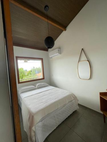 a bedroom with a bed with a window and a mirror at Vila Pimenta Rosa in Caraíva