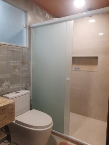 a bathroom with a toilet and a glass shower door at Casa - 1 Suíte e 2 Quartos in Saquarema