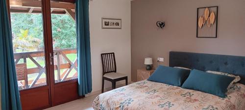 a bedroom with a bed and a chair and a window at Le Moulin du Comte in Bourrouillan