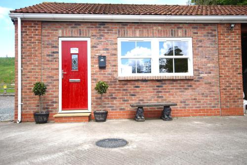 a brick house with a red door and a bench at Paull Holme Farm Bed and Breakfast in Paull