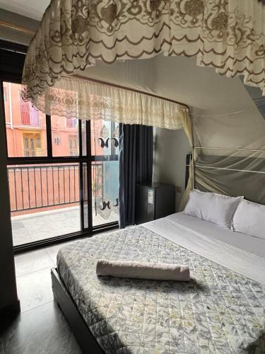 a bedroom with a bed with a canopy and a window at Icon Hotel in Kampala