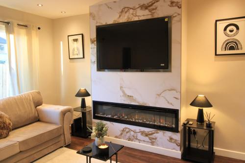 a living room with a flat screen tv above a fireplace at Edinburgh West Luxury 5 Bedroom Home in Edinburgh