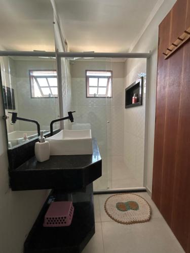 a bathroom with a sink and a shower with a mirror at CASA ESPAÇOSA e CONFORTÁVEL EM PARATY in Paraty