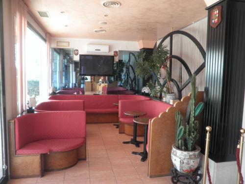 a waiting room with red chairs and a flat screen tv at Hotel Touring in Sottomarina