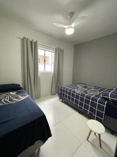 a bedroom with two beds and a ceiling fan at Achadinho no Coração de Aparecida 2 in Aparecida