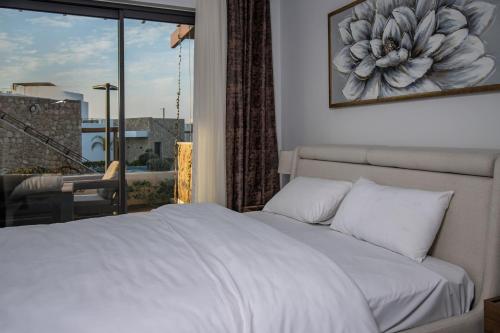 a bedroom with a white bed and a large window at Mykonos Holiday Homes in Kyrenia