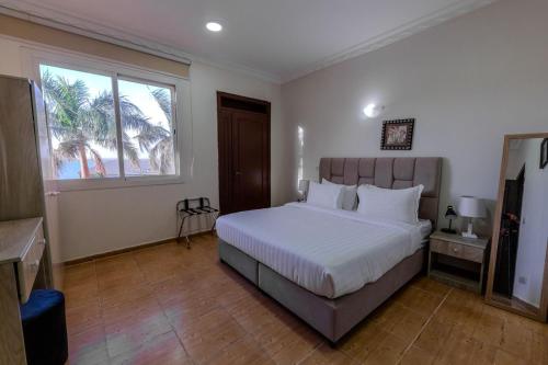 a bedroom with a bed with white sheets and a window at شاليهات الأحلام لبيوت العطلات in Yanbu