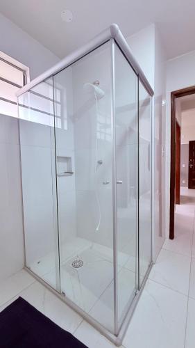 a large glass shower in a white room at Achadinho no Coração de Aparecida 2 in Aparecida
