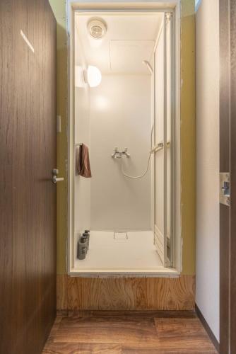 a bathroom with a shower with a glass door at Akabane Dormitory-Men Only in Tokyo