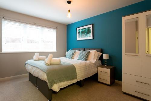 a bedroom with a bed with blue walls and a window at Beech Lodge Apartments, 2 Bed Apts close to Headington Hospitals in Oxford