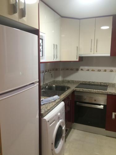 a kitchen with white cabinets and a washer at Levante Trip - Family Apartments in Benidorm