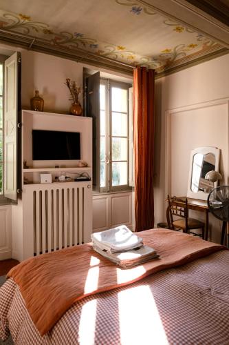 a bedroom with a bed with a tv on the wall at Maison Sumiane - Maison d hotes et locations avec piscine in Brignoles