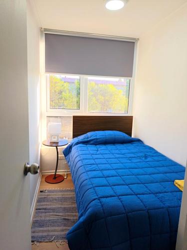 a bedroom with a blue bed and a window at Departamento Corcovado in Puerto Montt
