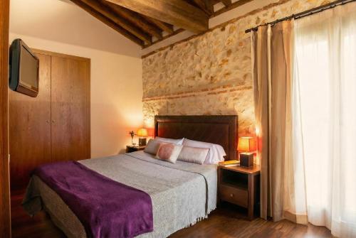 a bedroom with a large bed and a stone wall at El Pontifical in Los Santos de la Humosa