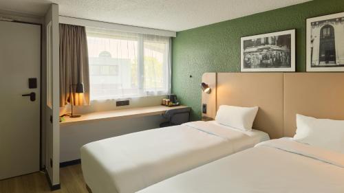 a hotel room with two beds and a window at Campanile NATURE - Saint-Germain-en-Laye in Saint-Germain-en-Laye