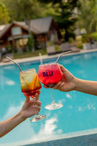 two people holding drinks in their hands near a pool at Guardianes Del Bayo in Villa La Angostura