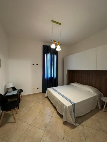 a bedroom with a bed and a chair and a window at La Casa del Corso in Bari Sardo