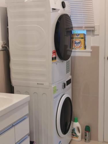 a washing machine with a microwave on top of it at Sweet North Cote Stay in Auckland