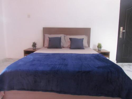 a bedroom with a blue bed with two pillows at Rams Lodge in Accra