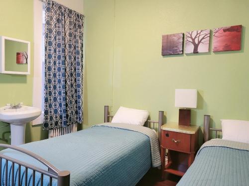 two twin beds in a room with a sink and a bathroom at Orange Village Hostel in San Francisco