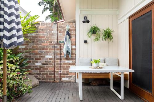 a white table on a patio with a brick wall at Alcorn Garden Studio - Dog friendly 2 mins walk to beach in Suffolk Park