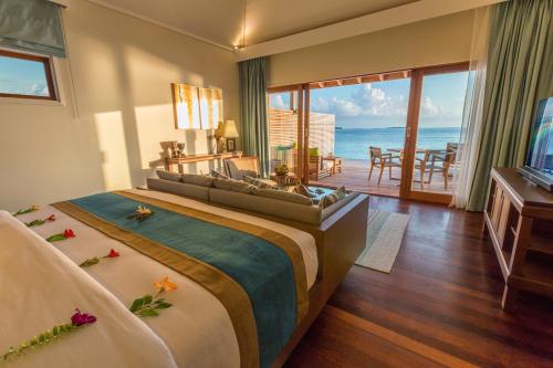 
a hotel room with a bed, table, chairs and a window at Hurawalhi Island Resort in Kuredu
