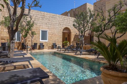 a pool with chairs and trees in a courtyard at Palazzo Pisani Boutique Hotel & Spa Malta in Żabbar
