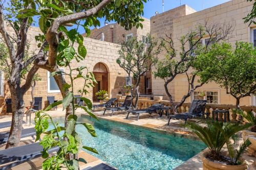 a pool in a courtyard with chairs and trees at Palazzo Pisani Boutique Hotel & Spa Malta in Żabbar