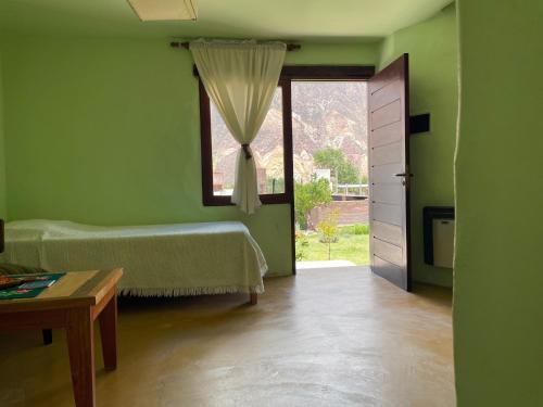 a green room with a bed and a window at Balcones del Pintor in Maimará