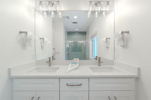 a white bathroom with two sinks and a mirror at Beach Nuts by Sun Palace Vacations in Fort Myers Beach