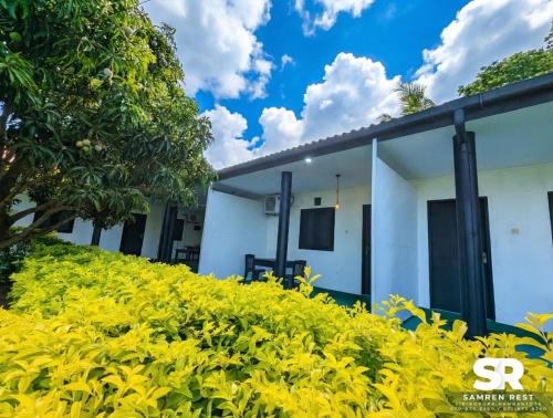 a white building with yellow bushes in front of it at Samren Rest in Hambantota