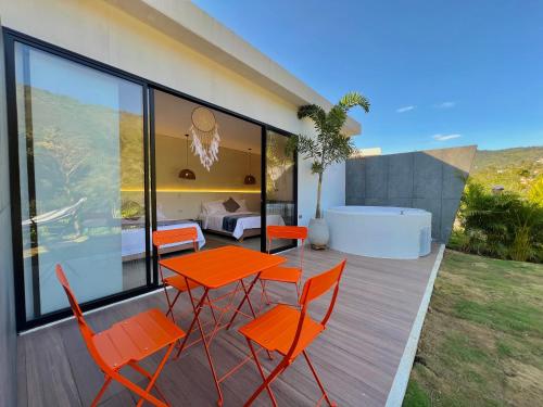 a deck with orange chairs and a table and a bedroom at Glamping Del Río by Trip Monkey in San Gil