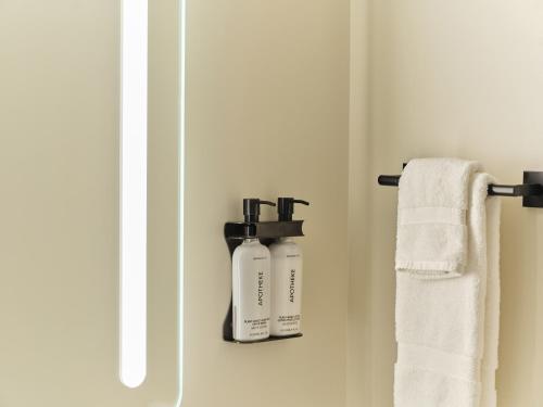 two bottles ofodorizers are on a shelf in a bathroom at Ambros Daytona, Trademark Collection by Wyndham in Daytona Beach