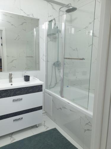 a white bathroom with a shower and a sink at Botanica Aeroport in Chişinău