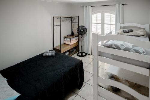 a bedroom with two bunk beds and a fan at Casa Aconchego da Bisa - perto do Estádio do Operário! in Ponta Grossa