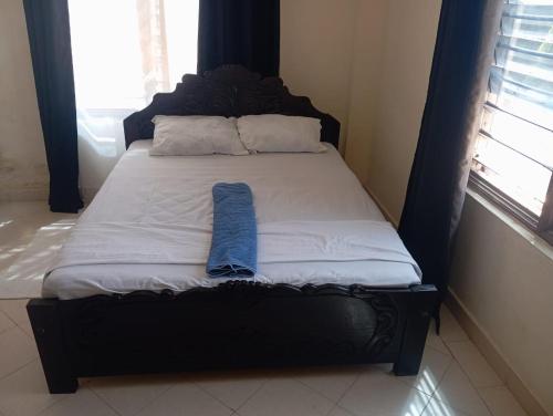 a bed with a black headboard with a blue towel on it at Nest Apartment Diani in Diani Beach