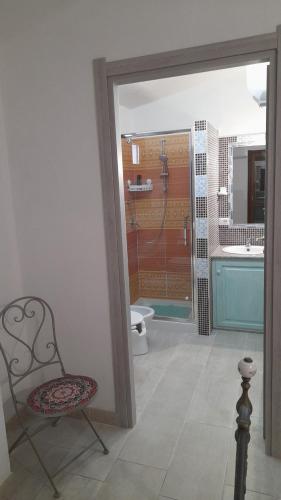 a bathroom with a shower and a chair and a toilet at Casa Grazia Deledda 16 in Orosei
