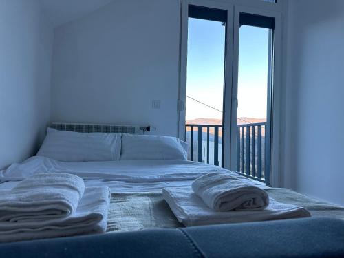a bed with towels on it in a room with a balcony at Villa Sunshine Brezovicë in Brezovica