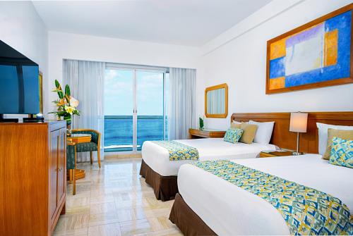 a hotel room with two beds and a television at Ocean Breeze Nuevo Vallarta in Nuevo Vallarta