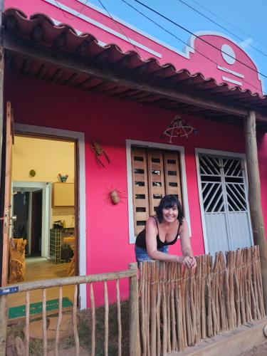a woman leaning on a fence in front of a pink house at Casa Corrupião - Ilha do Ferro - Alagoas in Pão de Açúcar