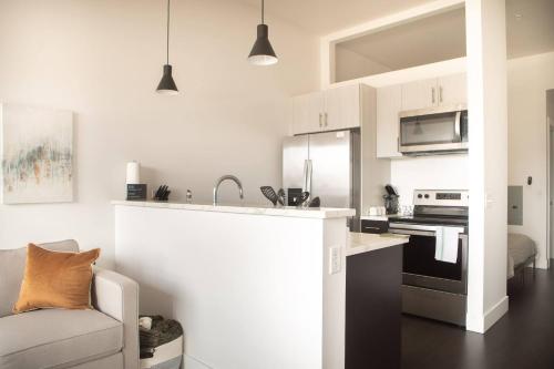 a kitchen with white cabinets and a stove top oven at Modern Studio Apt with Rooftop, Gym, and Parking in Milwaukee