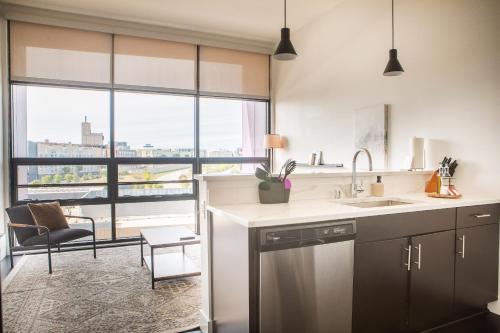 a kitchen with a sink and a large window at Modern Studio Apt with Rooftop, Gym, and Parking in Milwaukee