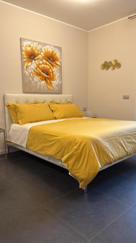 ein Bett mit gelben Laken und ein Gemälde an der Wand in der Unterkunft Bloom Apartment in Pero